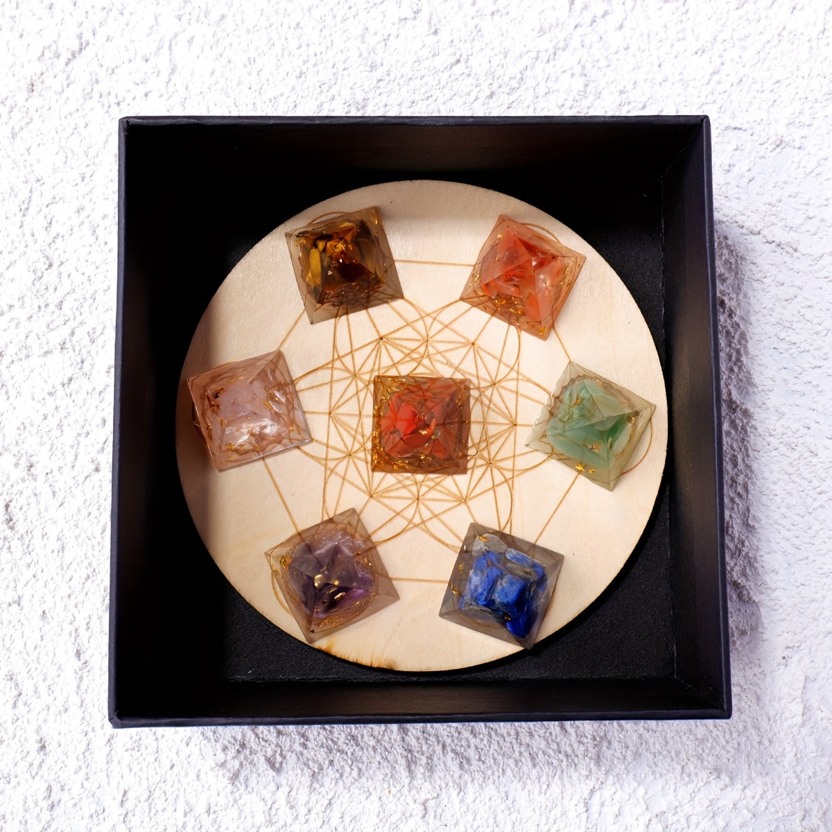 Chakra pyramid set presented inside an elegant black gift box, aligned over Metatron’s Cube for a visually harmonious energy display.