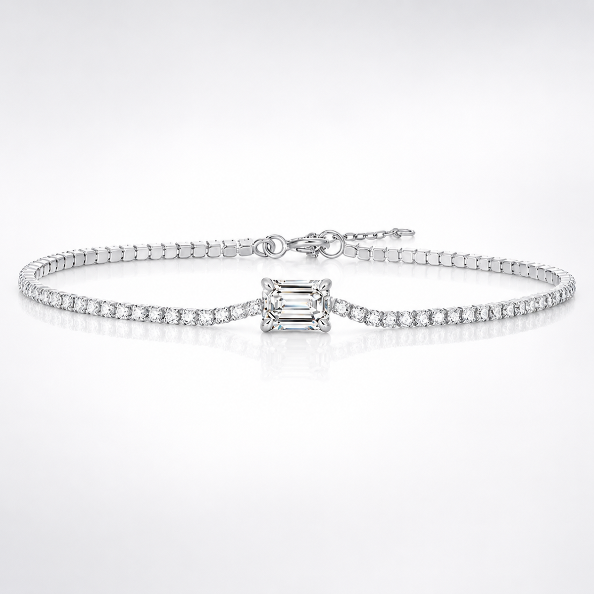 Silver emerald-cut moissanite tennis bracelet with round stone accents and extender chain on white
