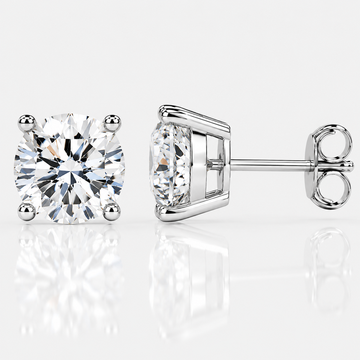 Silver four-prong colourless moissanite stud earrings shown front and side on a white background