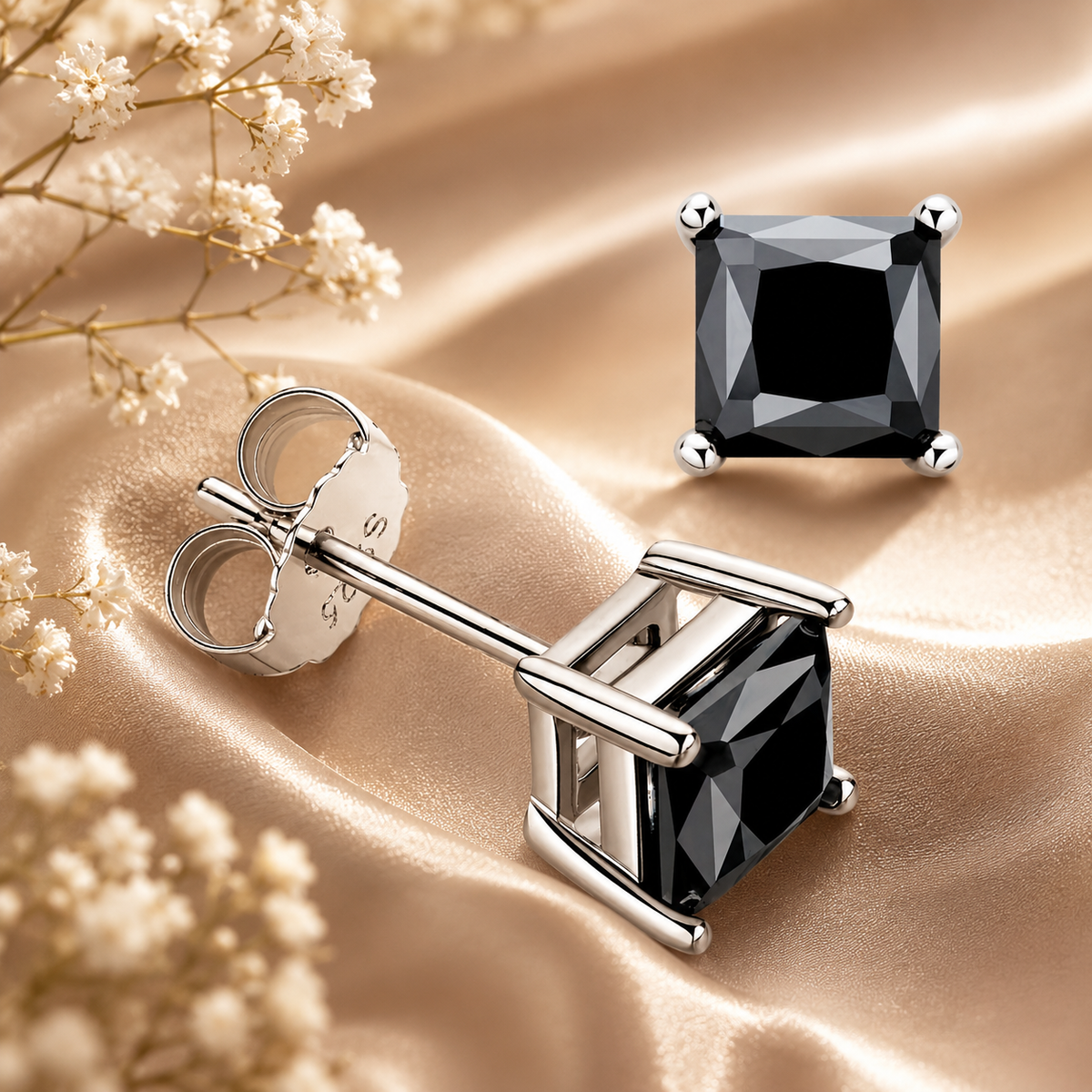 Silver princess cut black moissanite stud earrings displayed on champagne satin