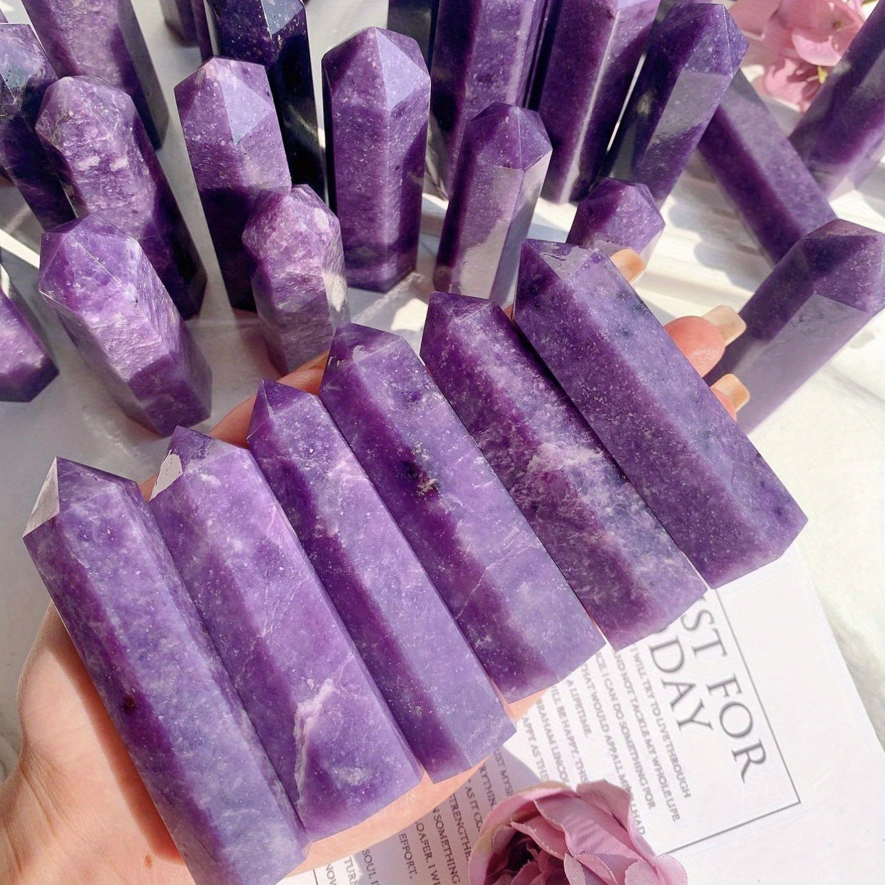 Dozens of Lepidolite crystal towers in various shades of purple displayed in natural sunlight, ideal for holistic healing, sleep support, and spiritual décor.