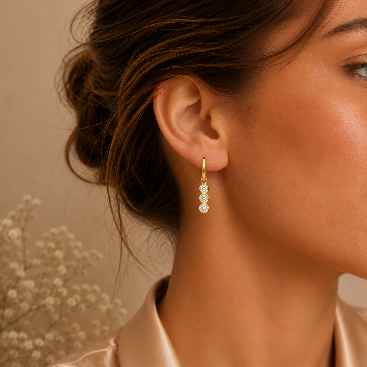 Gold triple-drop moissanite hoop earring worn on the ear in a close-up lifestyle view
