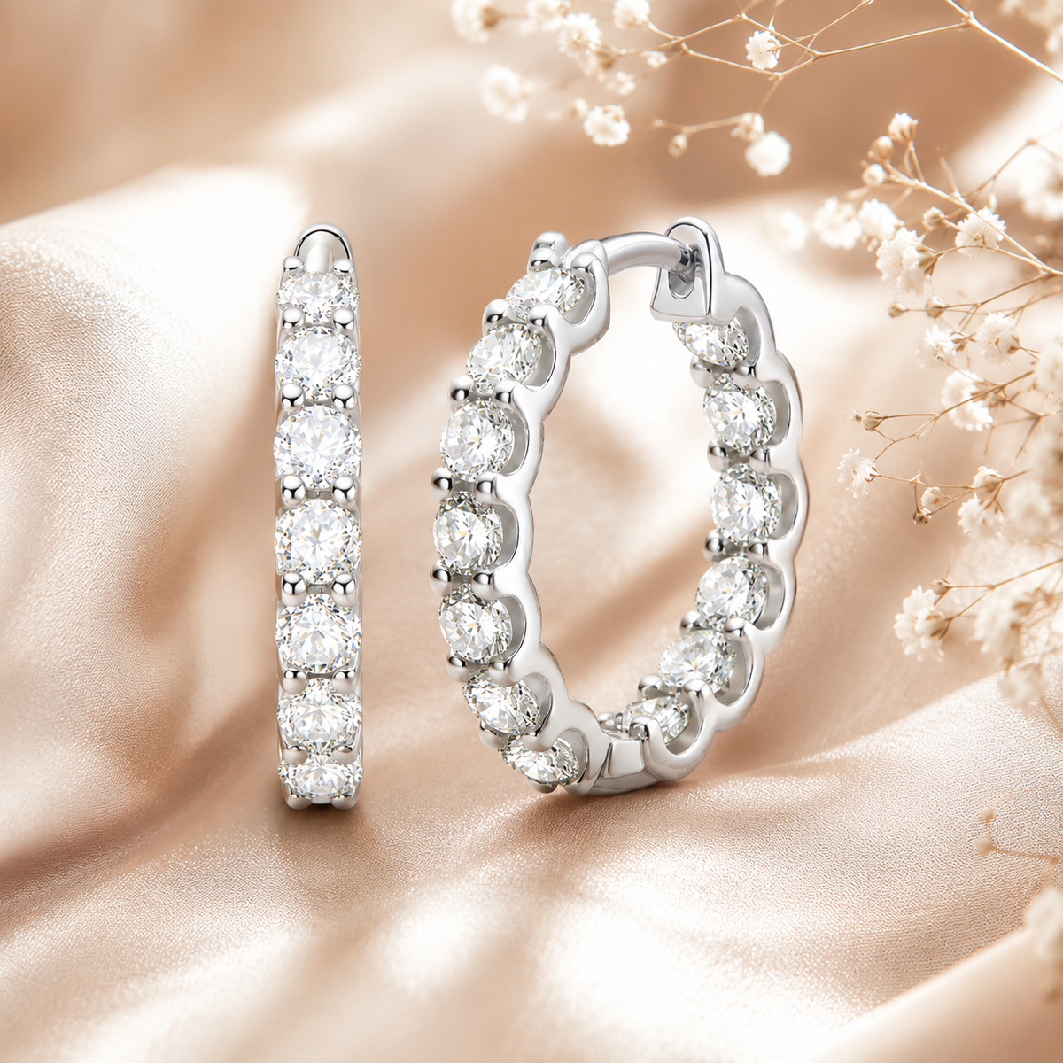 Silver inside-out moissanite hoop earrings displayed on champagne satin with flowers
