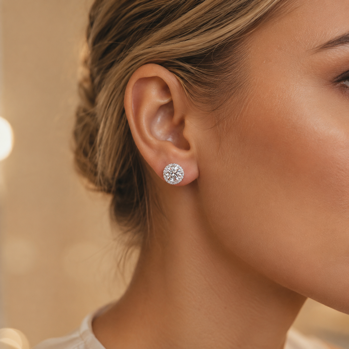 Round halo moissanite stud earring worn on the ear in a warm lifestyle close-up