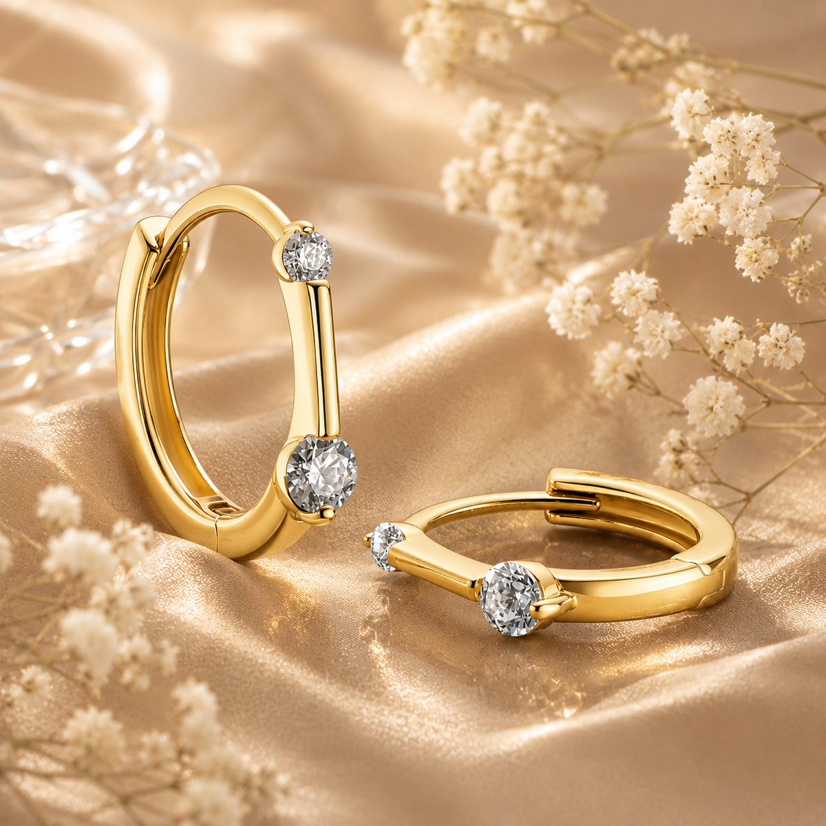 Gold floating moissanite hoop earrings displayed on champagne satin with dried flowers
