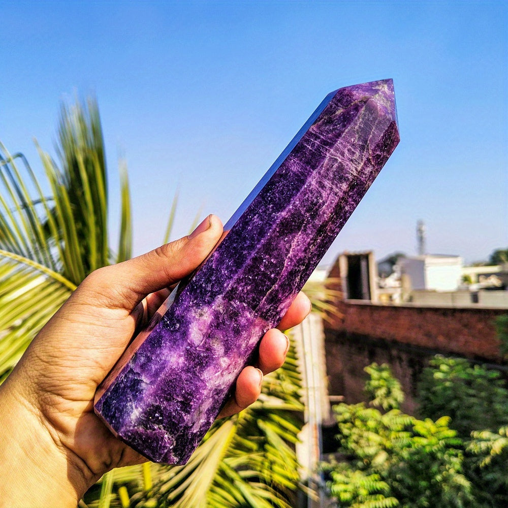 Person holding a tall polished Lepidolite wand under blue sky, featuring intense purple tones and mineral striations for meditation and grounding energy.