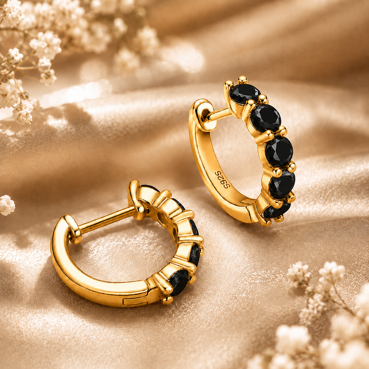 Back and side view of gold five-stone hoop earrings with black moissanite on champagne satin