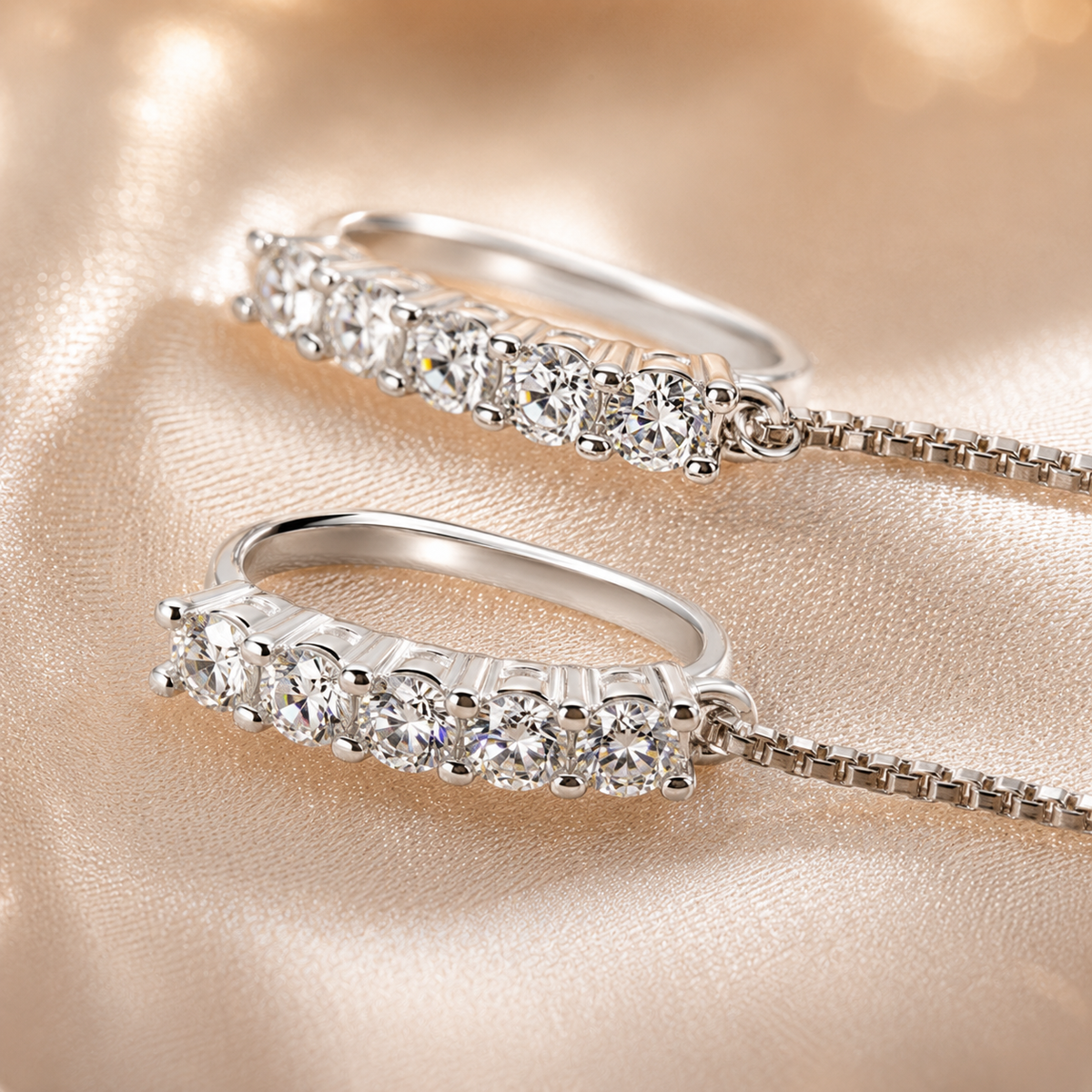 Macro close-up of the silver stone-set curved tops of moissanite threader chain earrings