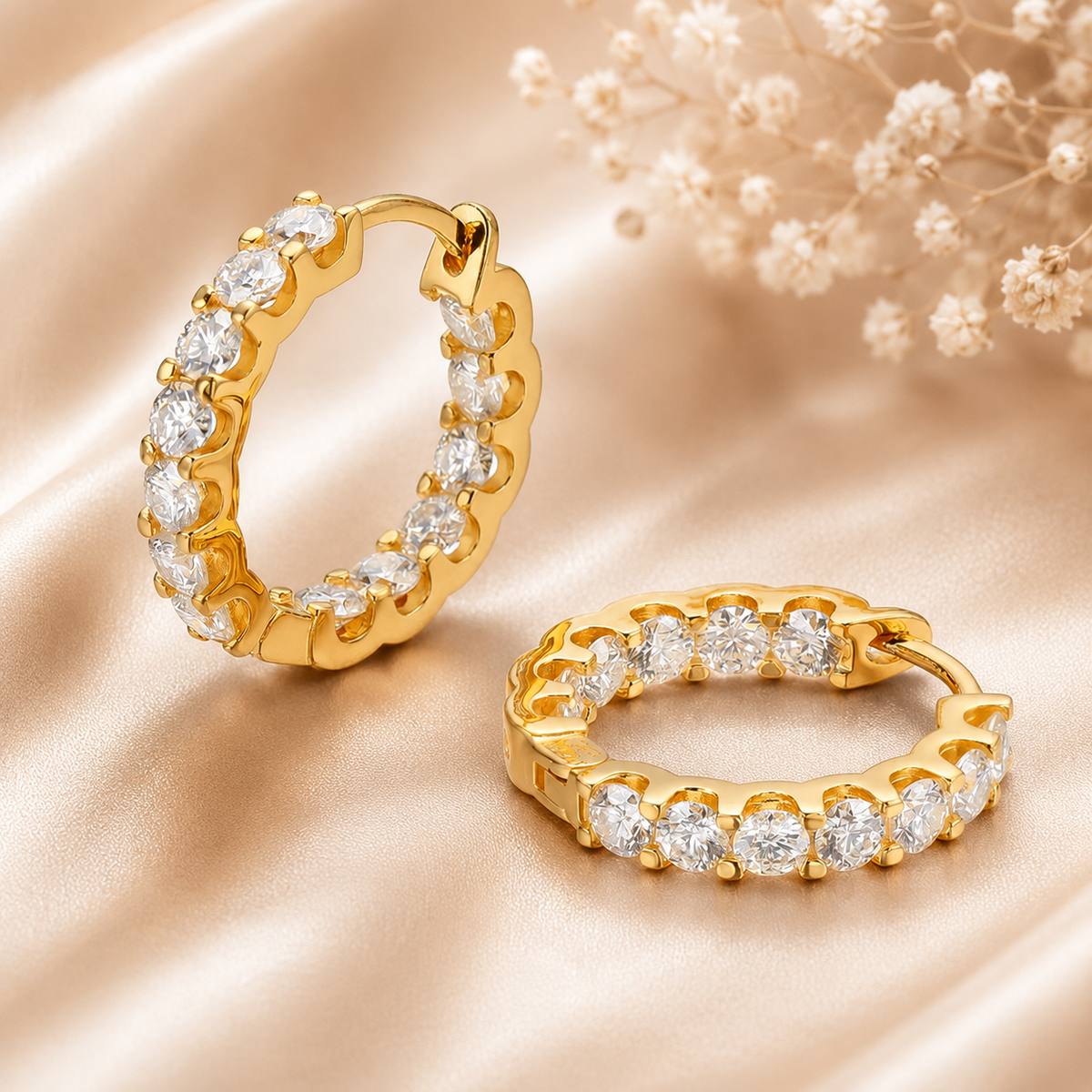 Gold inside-out moissanite hoop earrings displayed on champagne satin