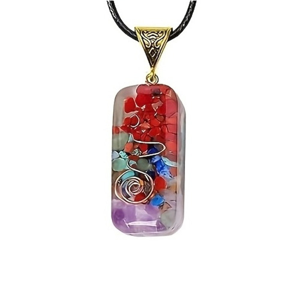 Rounded rectangular chakra pendant necklace with visible copper spiral and layers of red jasper, turquoise, green aventurine, and amethyst chips.