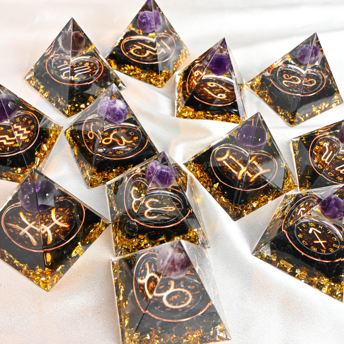 Diagonal layout of 12 zodiac orgone pyramids, each with amethyst sphere and intricate copper detailing.