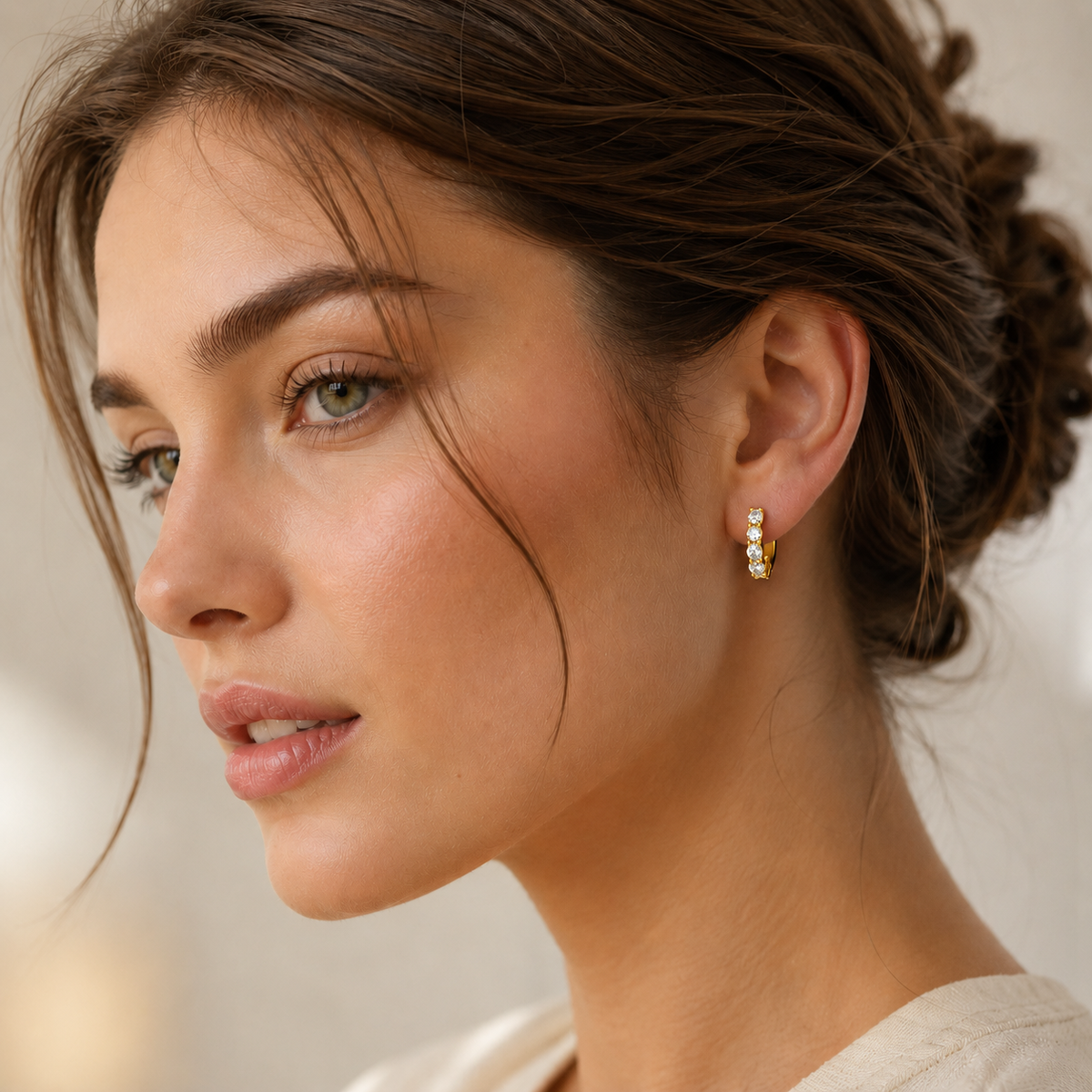 Gold five-stone moissanite hoop earring worn on the ear in a lifestyle close-up