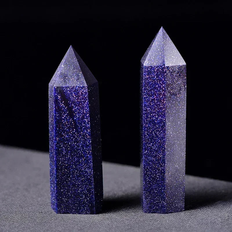 Two shimmering blue sandstone crystal towers with a deep navy base and reflective specks, displayed upright on a grey surface. Used to boost ambition, confidence, and focus.