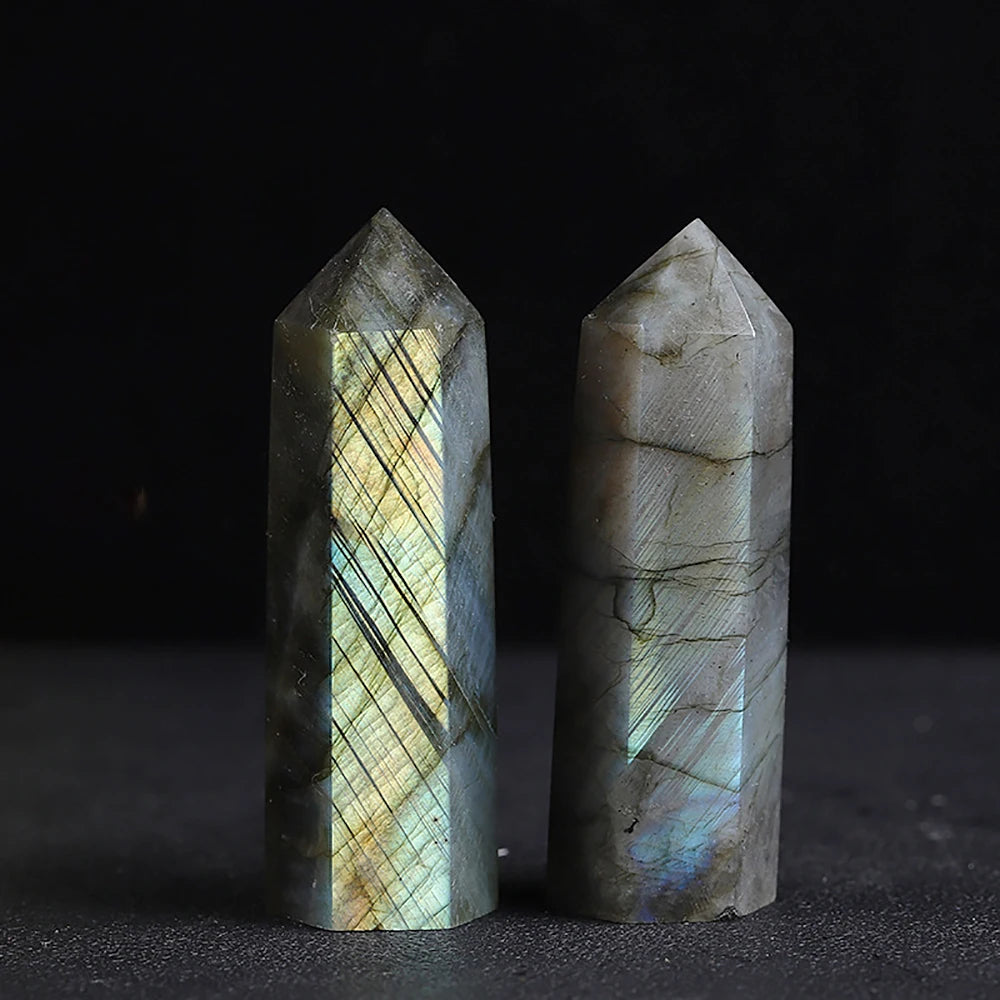 Pair of labradorite crystal towers with glowing reflections and natural inclusions displayed on a dark background.