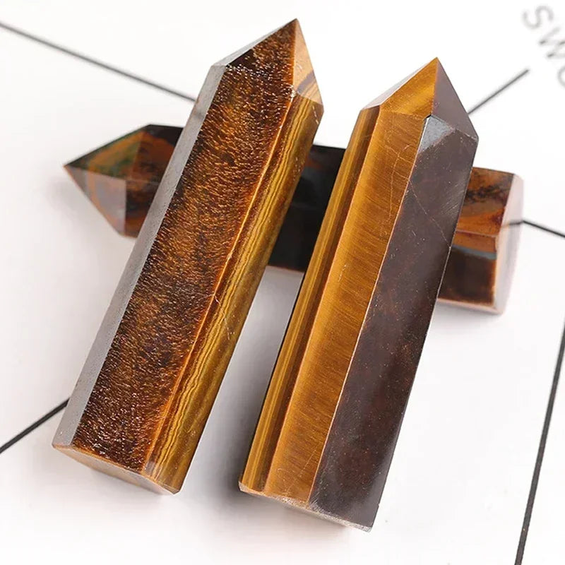 Polished tiger’s eye crystal towers with golden-brown bands and natural shimmer, arranged on a white surface. Used for protection, confidence, and grounding energy.