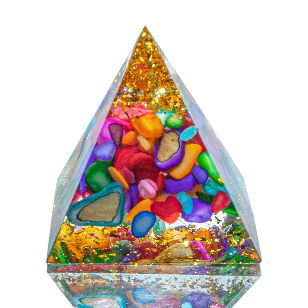 A close-up of a 3cm orgone pyramid featuring vibrant, polished agate stones in various colours, encased in clear resin with shimmering gold foil. Designed for chakra healing, EMF protection, and spiritual energy balancing.