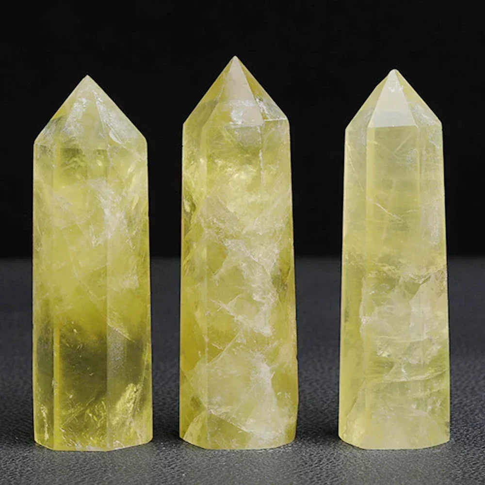 Three citrine crystal towers in light yellow hues with semi-translucent clarity, arranged against a dark background. Associated with prosperity, energy, and mental clarity.