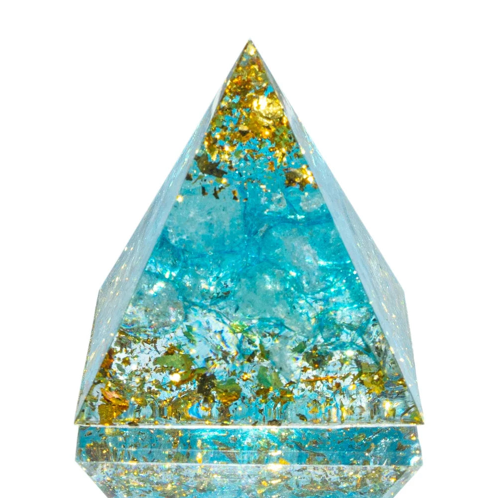 A 3cm orgone pyramid featuring soothing aquamarine crystals and sparkling gold foil flakes, set in clear resin. Crafted to promote calmness, emotional healing, and clear communication.