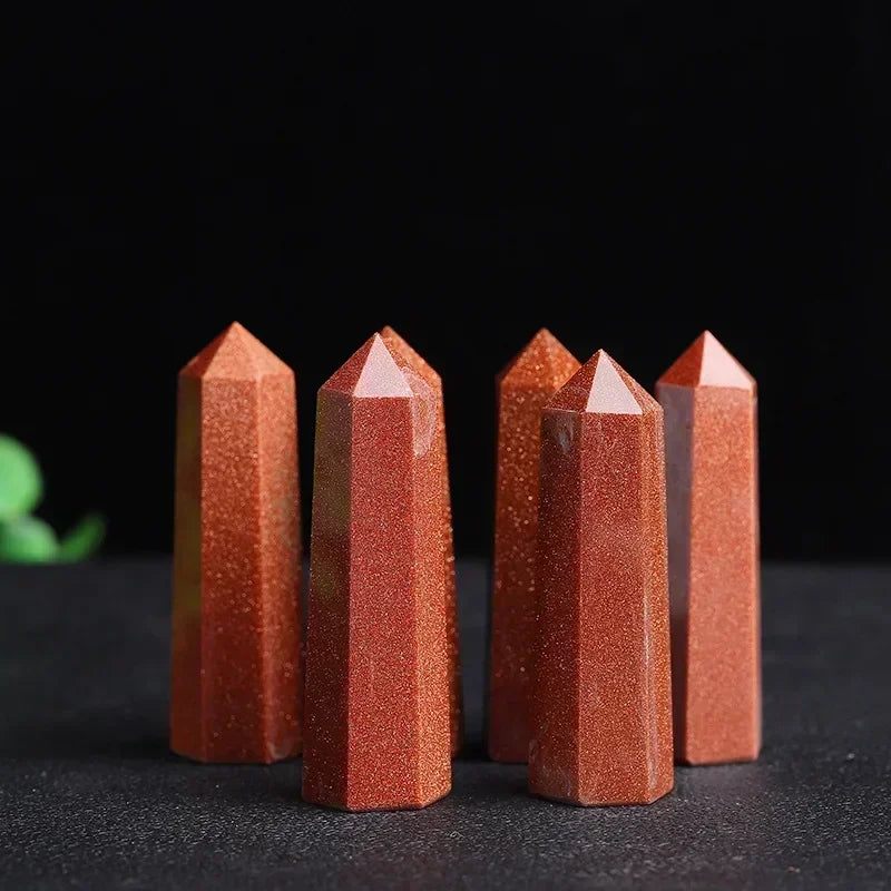 Five red sandstone crystal towers with a sparkling, glitter-like finish and deep coppery tones, arranged upright on a black surface. Used for confidence, creativity, and vitality.