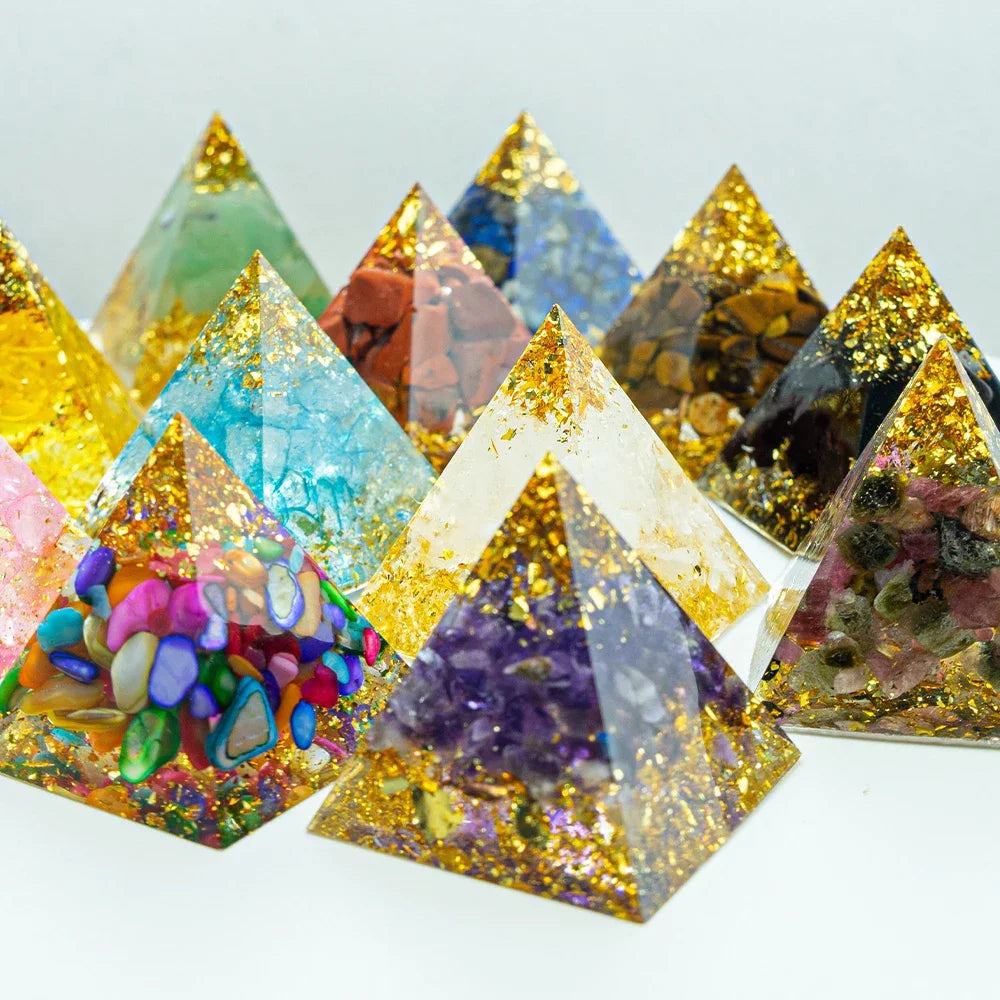 A colourful group of handcrafted 3cm orgone pyramids made with vibrant crystal chips, gold foil, and clear resin, arranged in a triangle formation on a white background. Designed for energy healing, chakra balancing, and EMF protection.