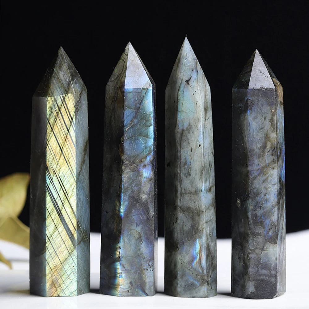 Four upright labradorite crystal towers with pointed tops against a dark background, each displaying unique iridescent striations.