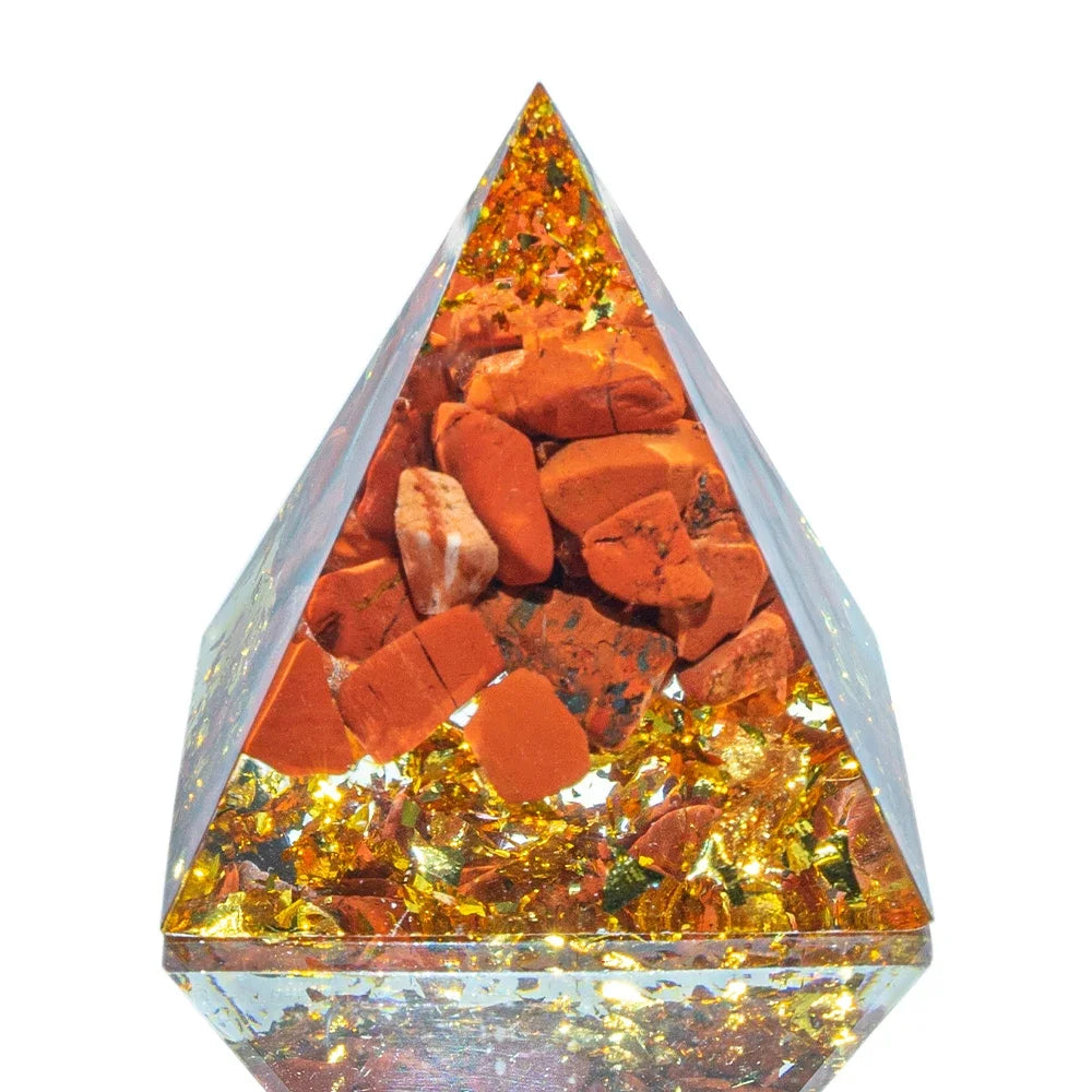 A 3cm orgone pyramid containing bold red jasper stones and gold foil flakes suspended in clear resin, crafted to promote strength, vitality, and grounding energy.