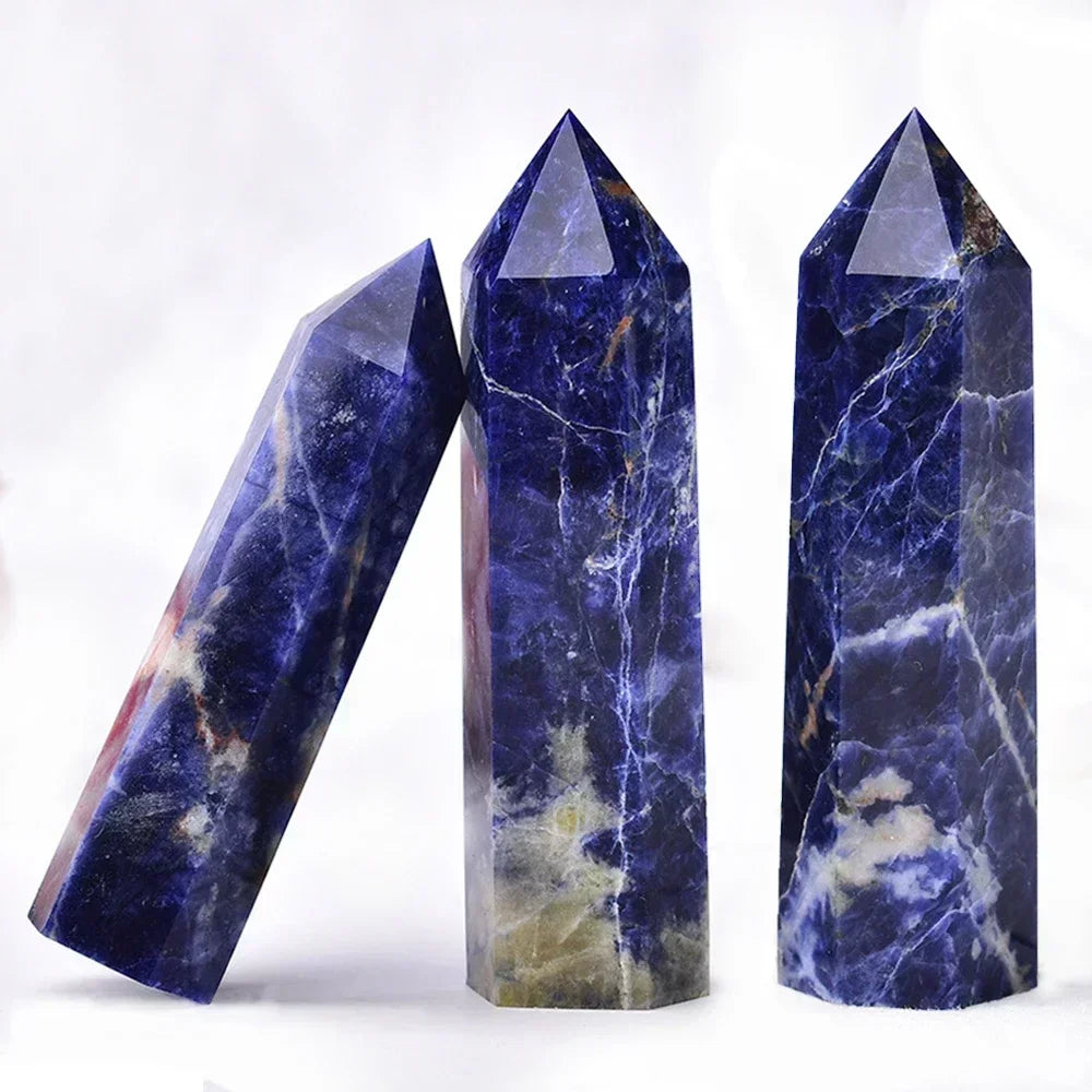Three deep blue sodalite crystal towers with white and beige marbling, arranged on a light surface. Ideal for intuition, truth, and emotional balance.