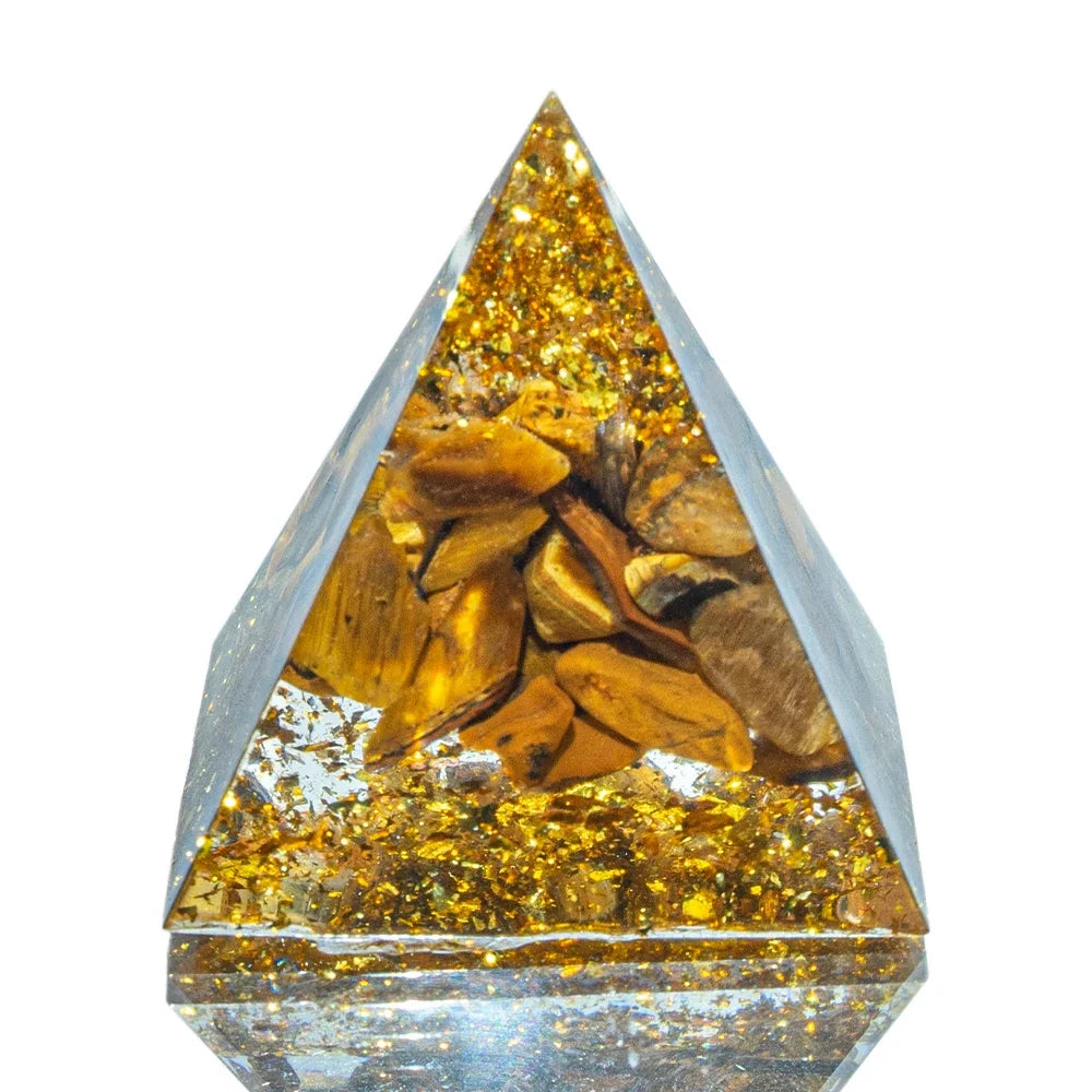 A 3cm orgone pyramid filled with golden-brown tiger’s eye stones and shimmering gold foil, encased in clear resin. Designed to enhance courage, focus, and grounding energy.
