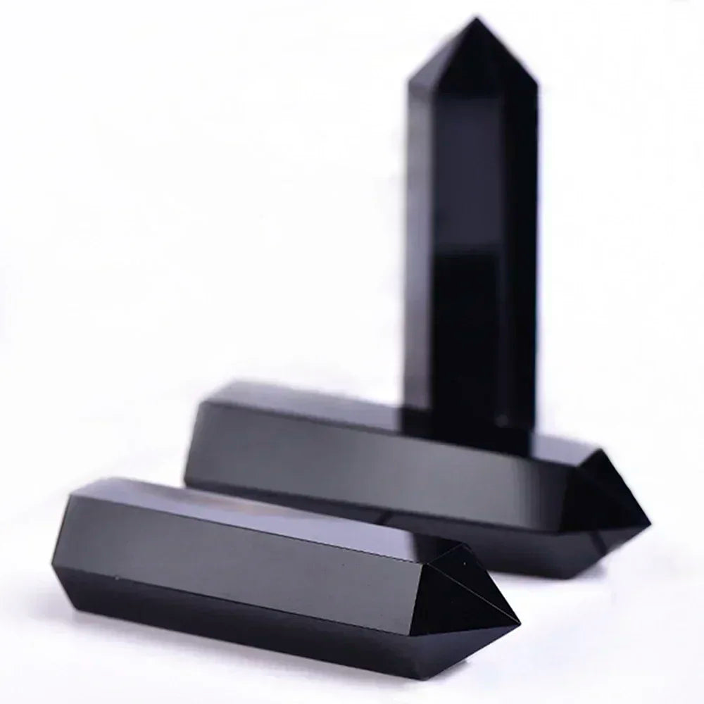 Three sleek and glossy black obsidian crystal towers arranged vertically and horizontally on a white background. Used for energetic protection and grounding negativity.