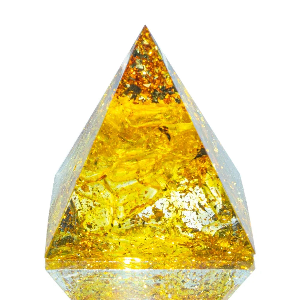 A 3cm orgone pyramid filled with golden yellow topaz crystals and sparkling gold foil, encased in clear resin, crafted for manifestation, confidence, and energy cleansing.