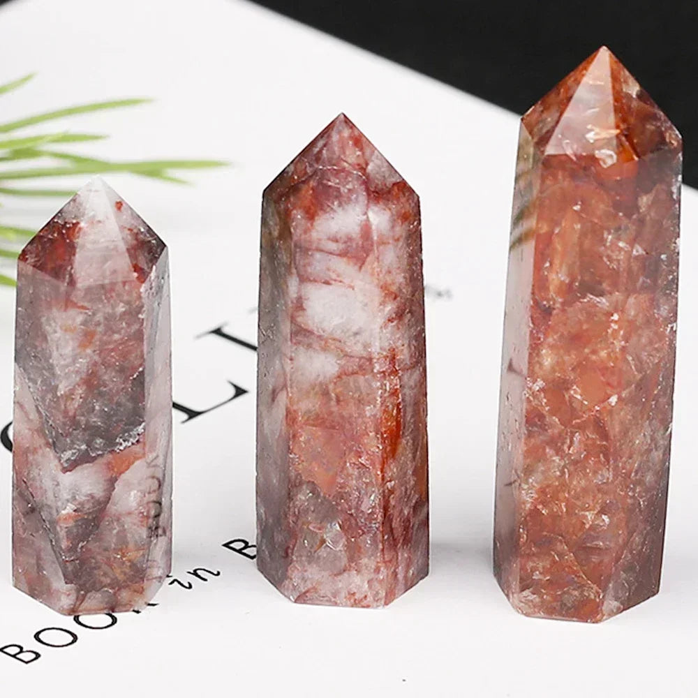 Three red gum flower quartz towers featuring cloudy red, white, and grey patterns, displayed on a white paper background. Known for grounding energy and heart healing.