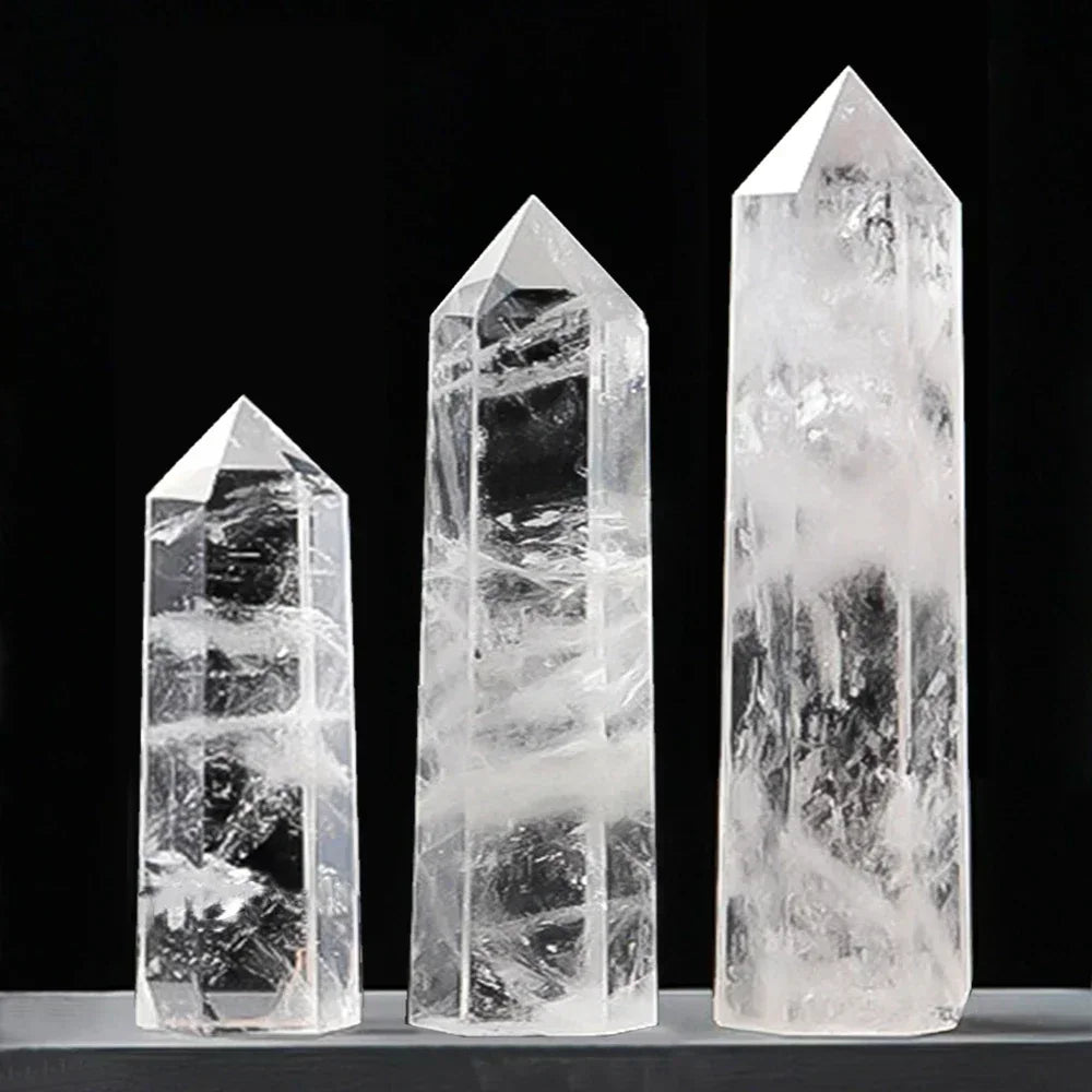 Three polished clear quartz crystal towers, semi-transparent with icy internal inclusions, displayed on a black background. Known as a master healer for energy amplification and clarity.