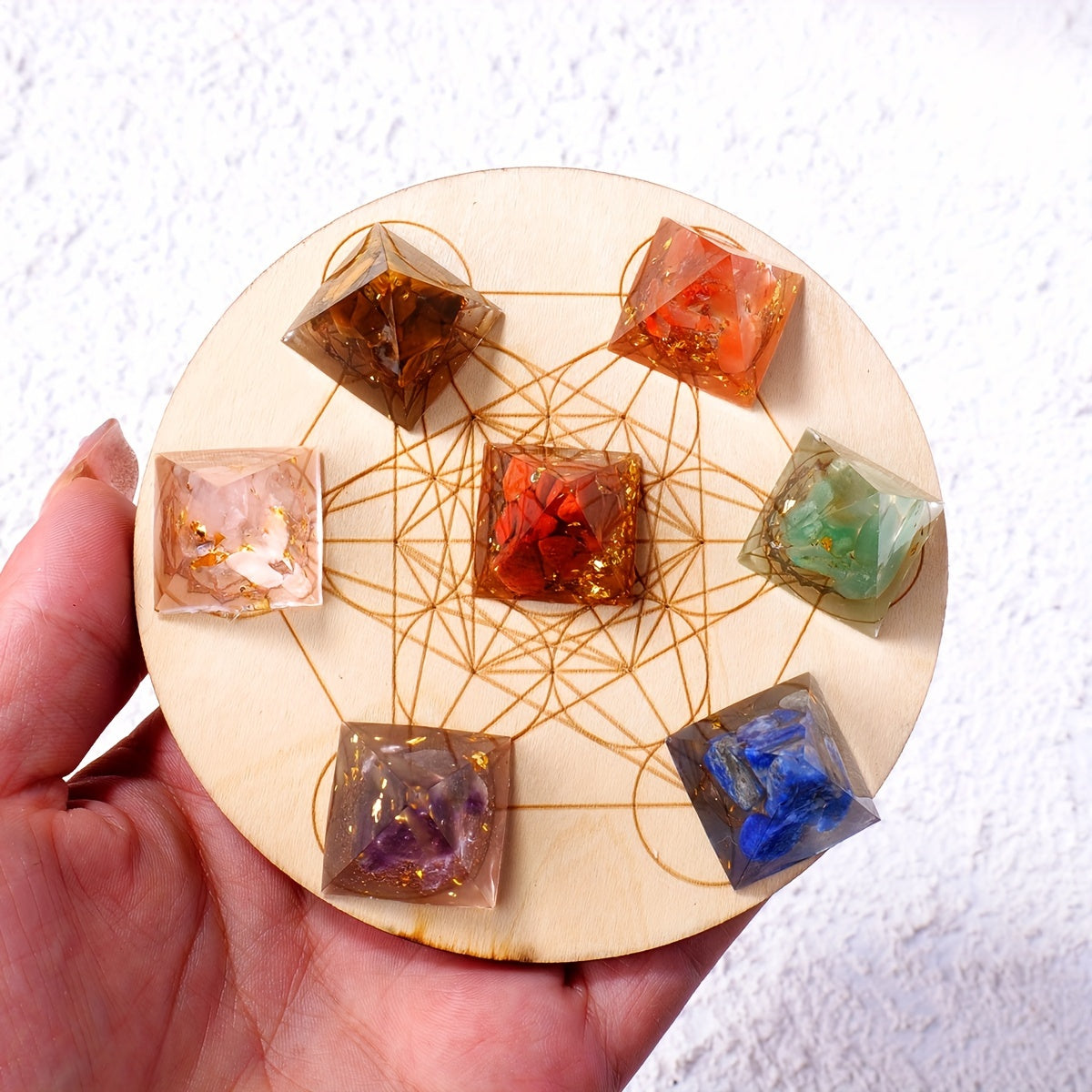 Close-up of the chakra crystal pyramids arranged on a Metatron’s Cube wooden grid, held in hand with visible crystal clarity and texture.