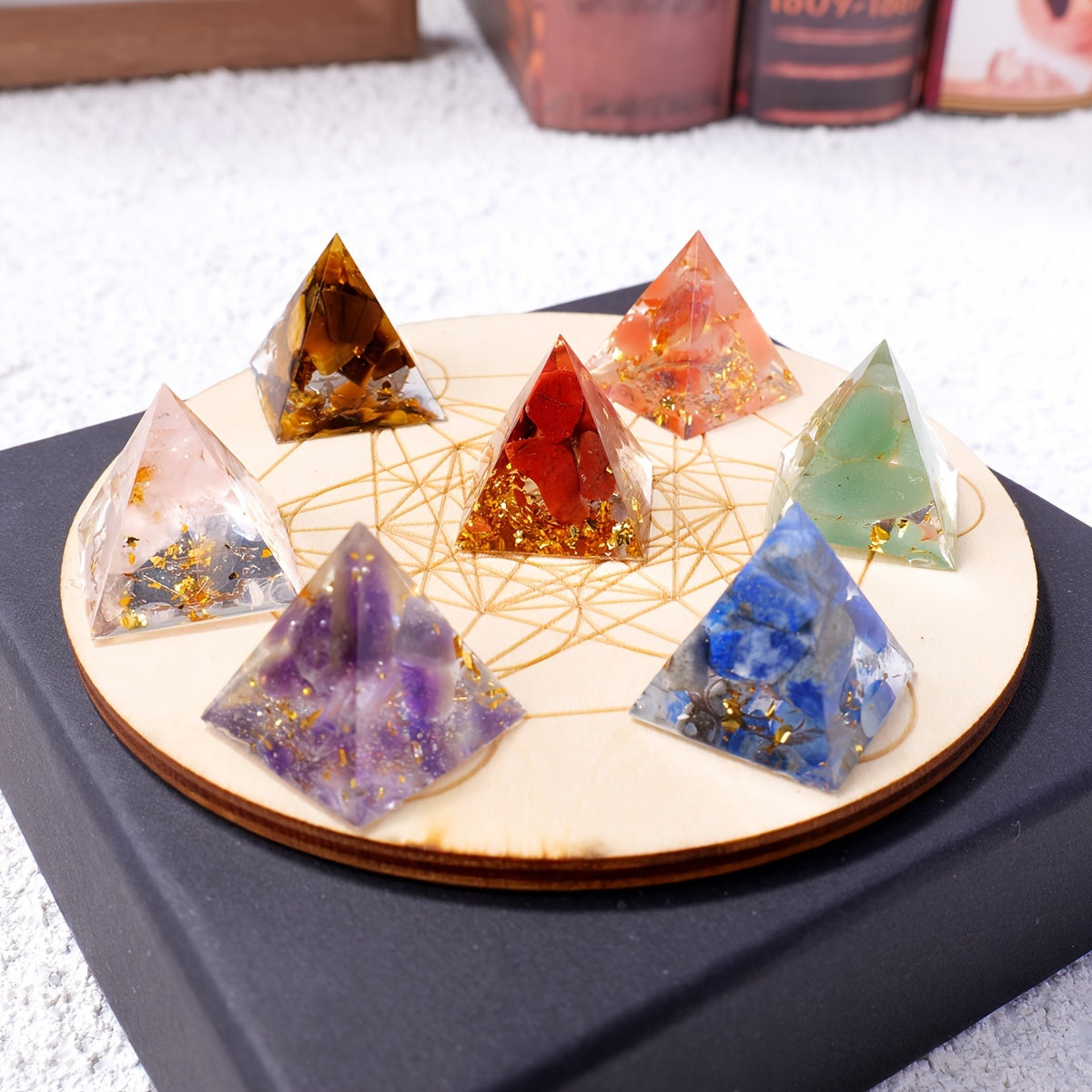Angled view of the pyramid set arranged on a sacred geometry disc, showcasing colourful natural crystals with embedded gold flakes.