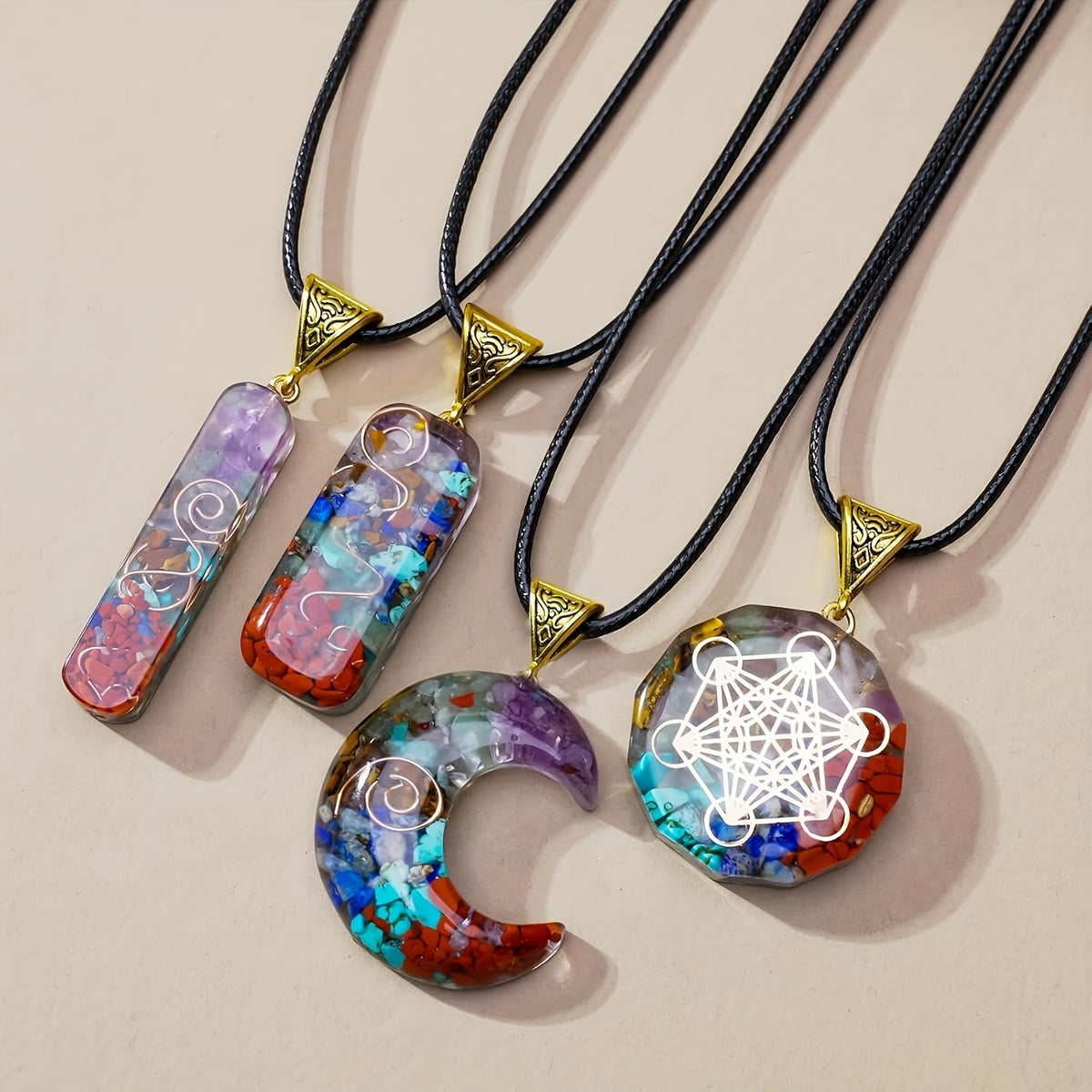 Close-up of chakra crystal pendant necklaces laid flat, highlighting intricate designs and embedded natural stones in each unique pendant shape.