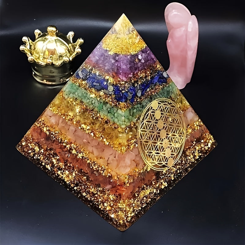 Side view of a vibrant orgone pyramid layered with chakra stones, featuring a golden Flower of Life, displayed beside healing décor.